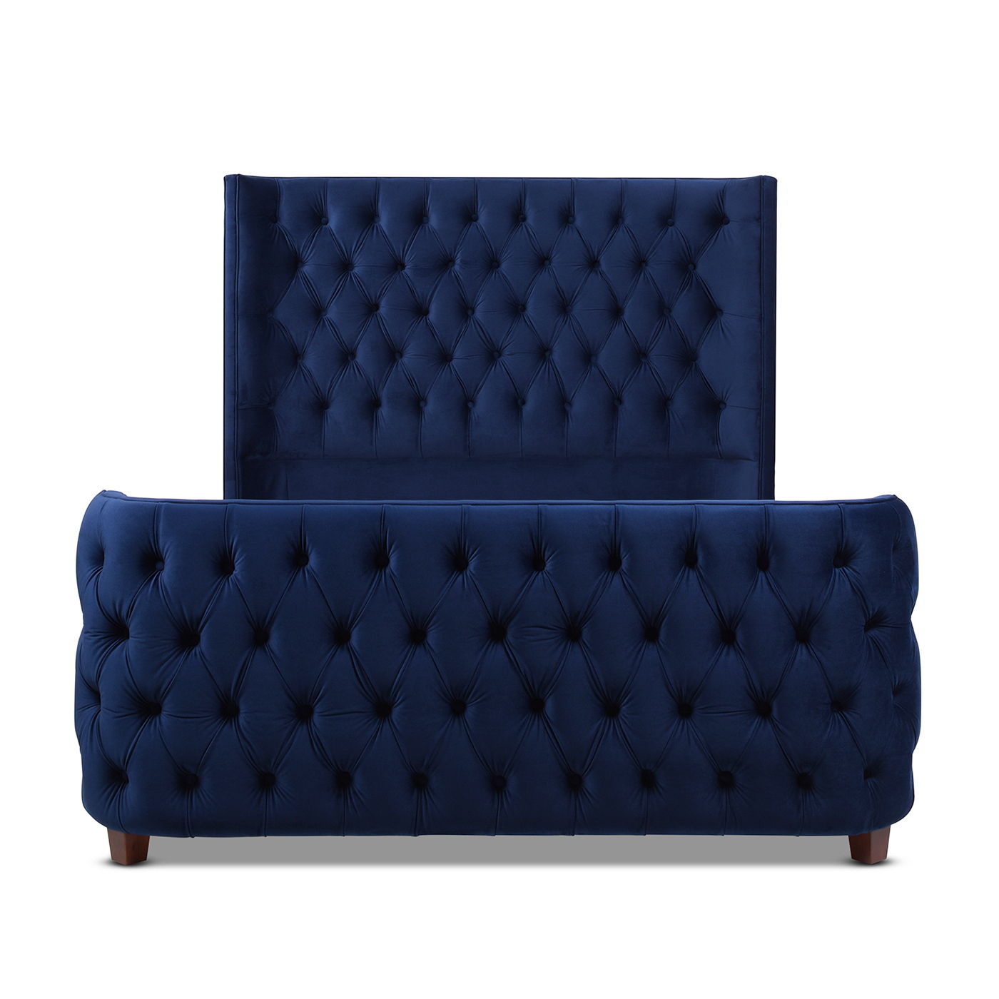 The Brooklyn Tufted Panel Bed features a navy blue velvet frame with high padded headboard and matching footboard, both showcasing diamond button tufting. It stands on short, dark wooden legs for a stylish finish.