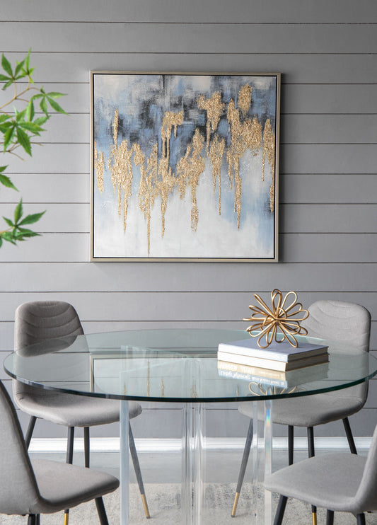 A modern dining area with four gray chairs around a round glass table displaying two books and a gold sculpture. On the gray shiplap wall hangs the Modern Oil Painting, Square Framed Wall Art For Living Room Dining Room Office - Multicolor.