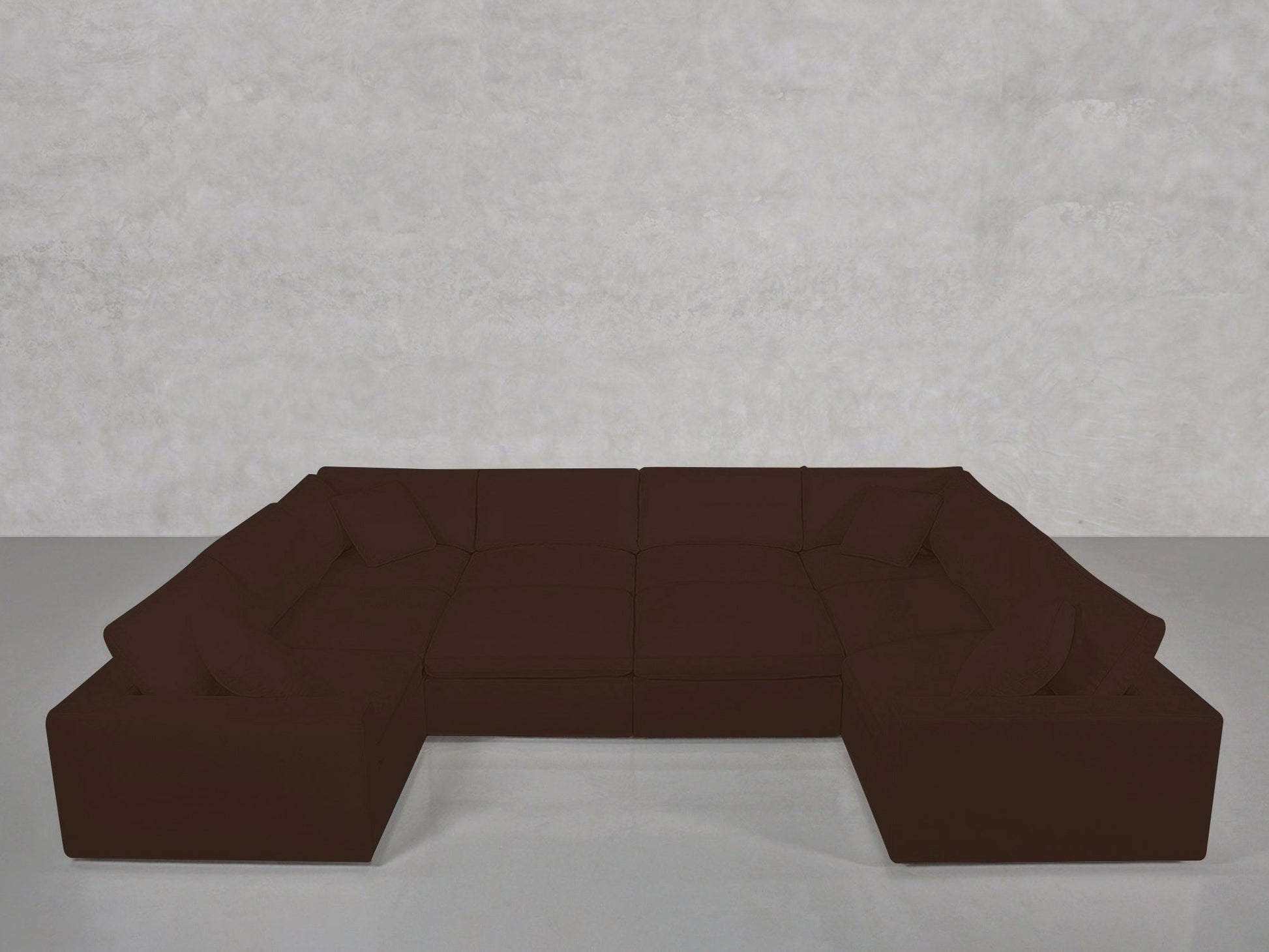 A 10-Seat Modular Closed Pit sectional in dark brown with multiple cushions forms a U-shape on a light grey floor against a textured light grey wall.