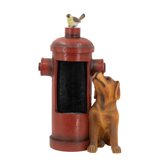 The Red Fire Hydrant Water Fountain With Dog And Bird Accents features a red hydrant with an open compartment, a brown dog sitting beside it, and a bird perched on top. Includes light and pump for outdoor use.