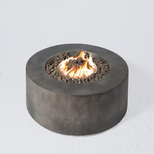 The Fibre Reinforced Outdoor Fire Pit Table - Charcoal features a round, modern design with a dark gray concrete finish, black lava rocks, and central flames, shown against a plain white background.
