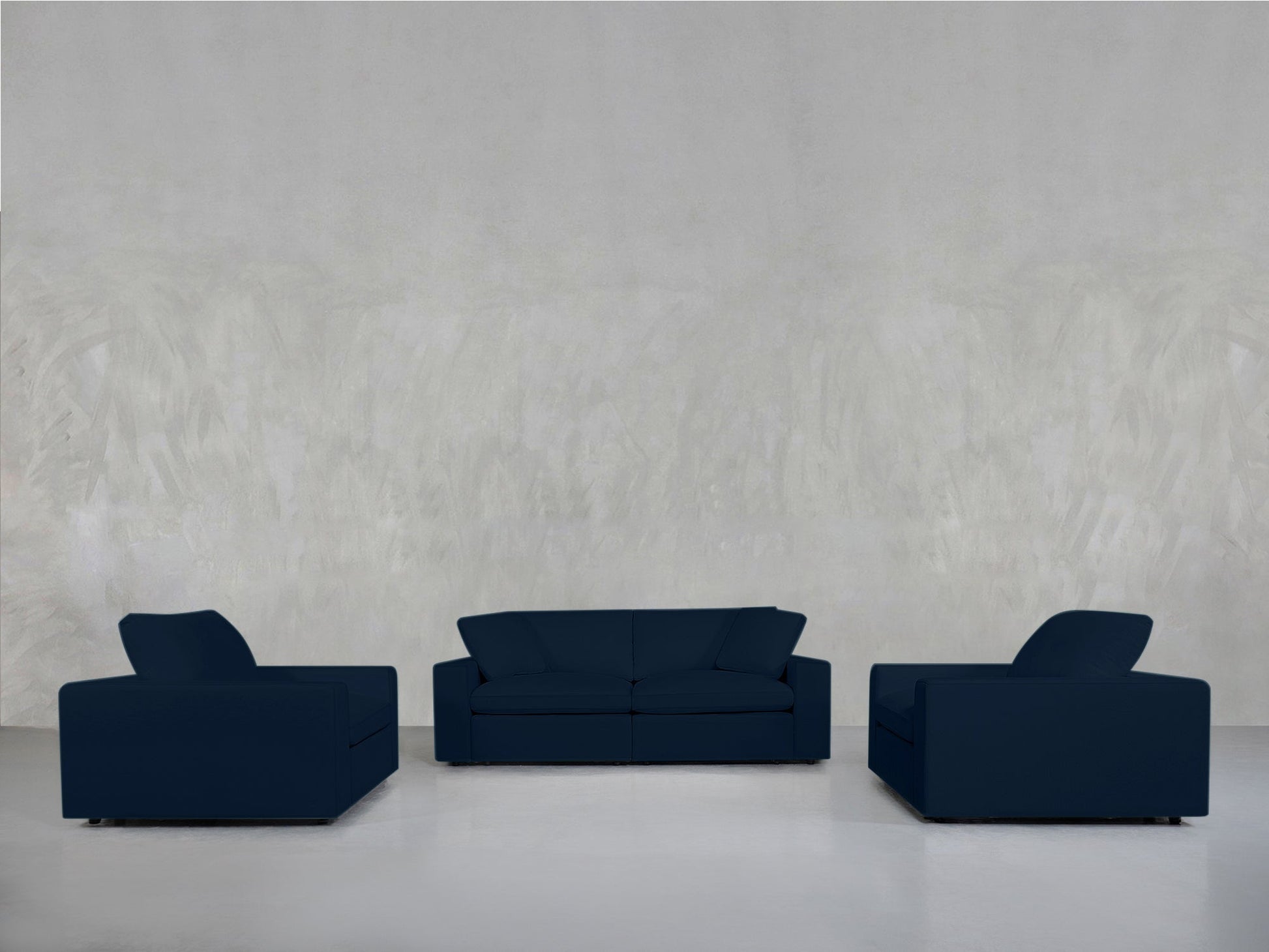 The 2-1-1 Sofa & Armchair Set in dark blue, featuring a central sofa and two armchairs, is arranged against a light gray textured wall on a glossy white floor.