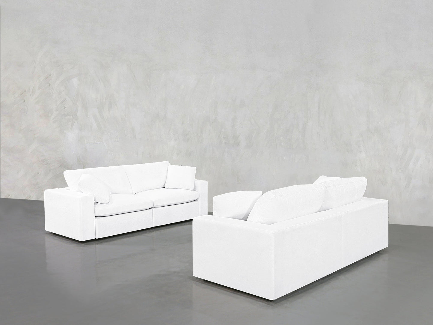 The 2-2 Sofa Set, featuring two modern white sofas with clean lines, is arranged on a glossy gray floor in a minimalist room accented by a textured light gray wall.