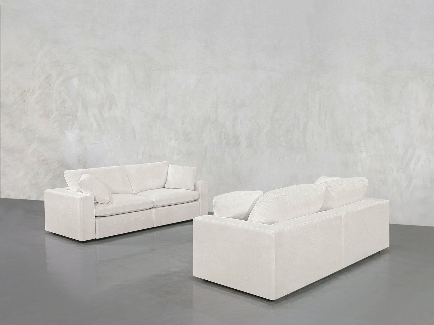 The 2-2 Sofa Set, featuring two modern white sofas with clean lines, is arranged facing each other in a spacious room with a light gray textured wall and glossy gray floor, creating a minimalist, open ambiance.