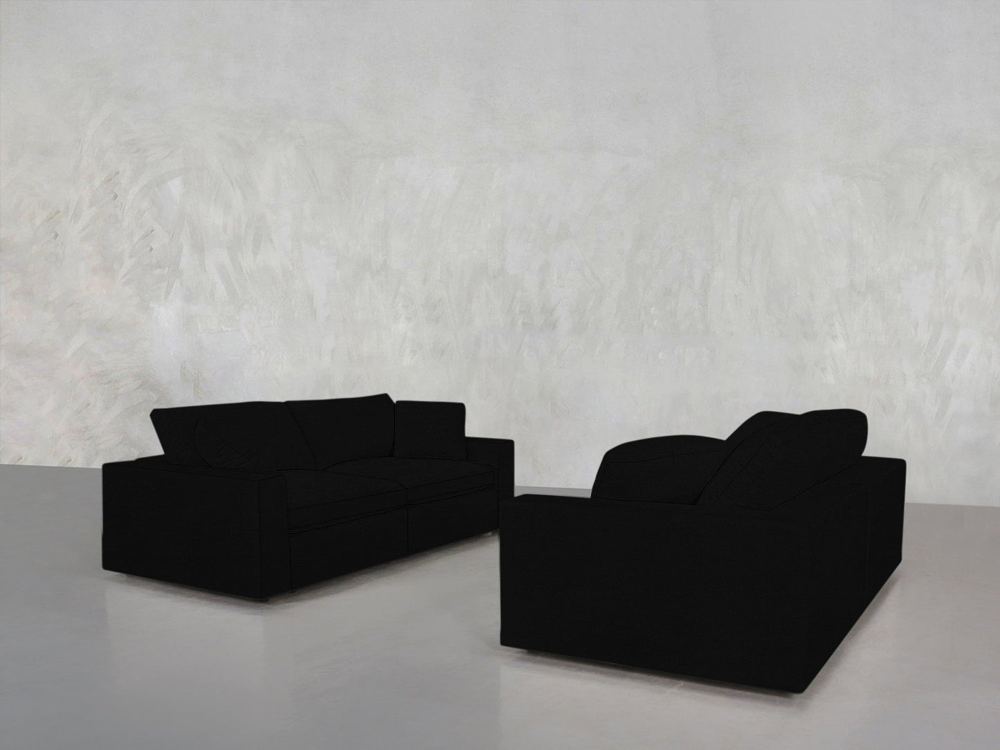 The 2-2 Sofa Set, in black, is arranged facing each other in a minimalist room with light gray textured walls and a smooth, light floor.