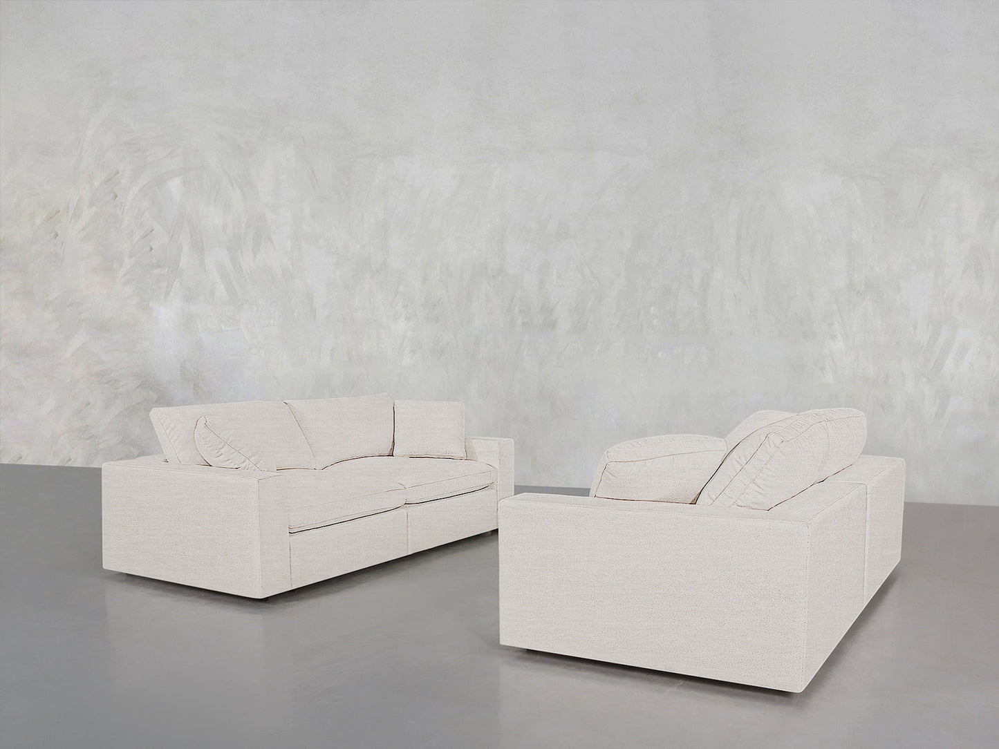 The 2-2 Sofa Set features two modern, light beige sofas with clean lines, placed on a polished gray floor against a textured, light wall for a minimalist and contemporary look.