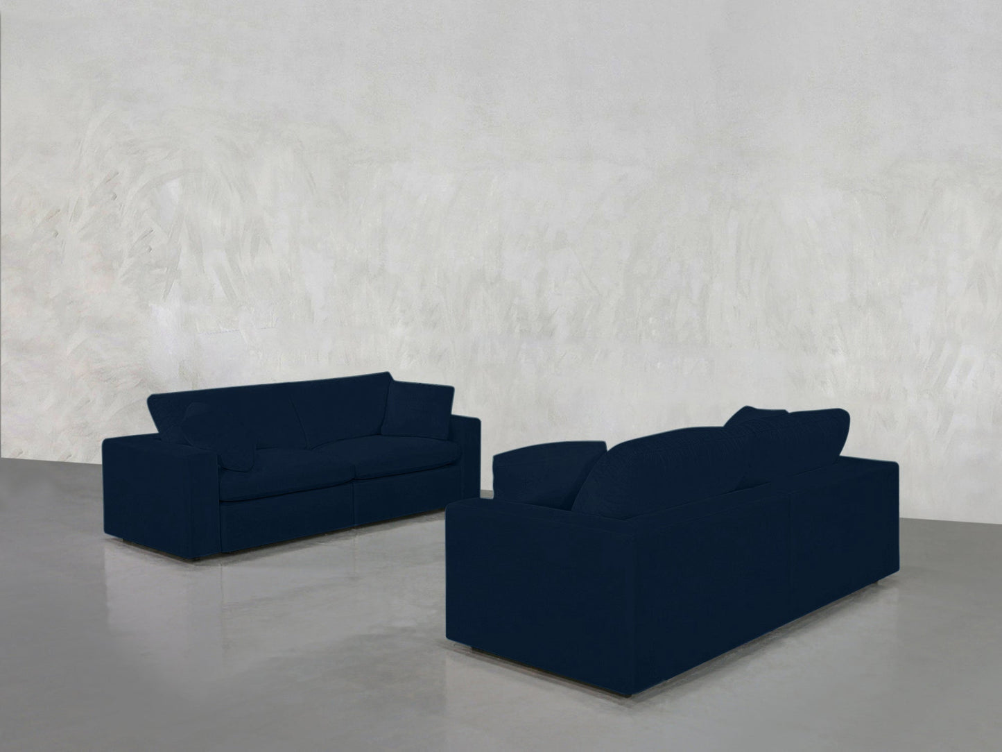 The 2-2 Sofa Set in dark blue faces itself in a minimalistic room with light gray textured walls and a glossy gray floor.