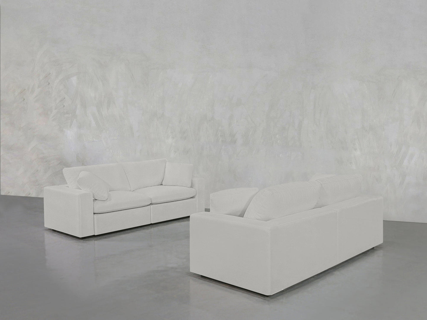 The 2-2 Sofa Set in modern white stands on a gleaming gray floor within a minimalist room featuring textured light gray walls.