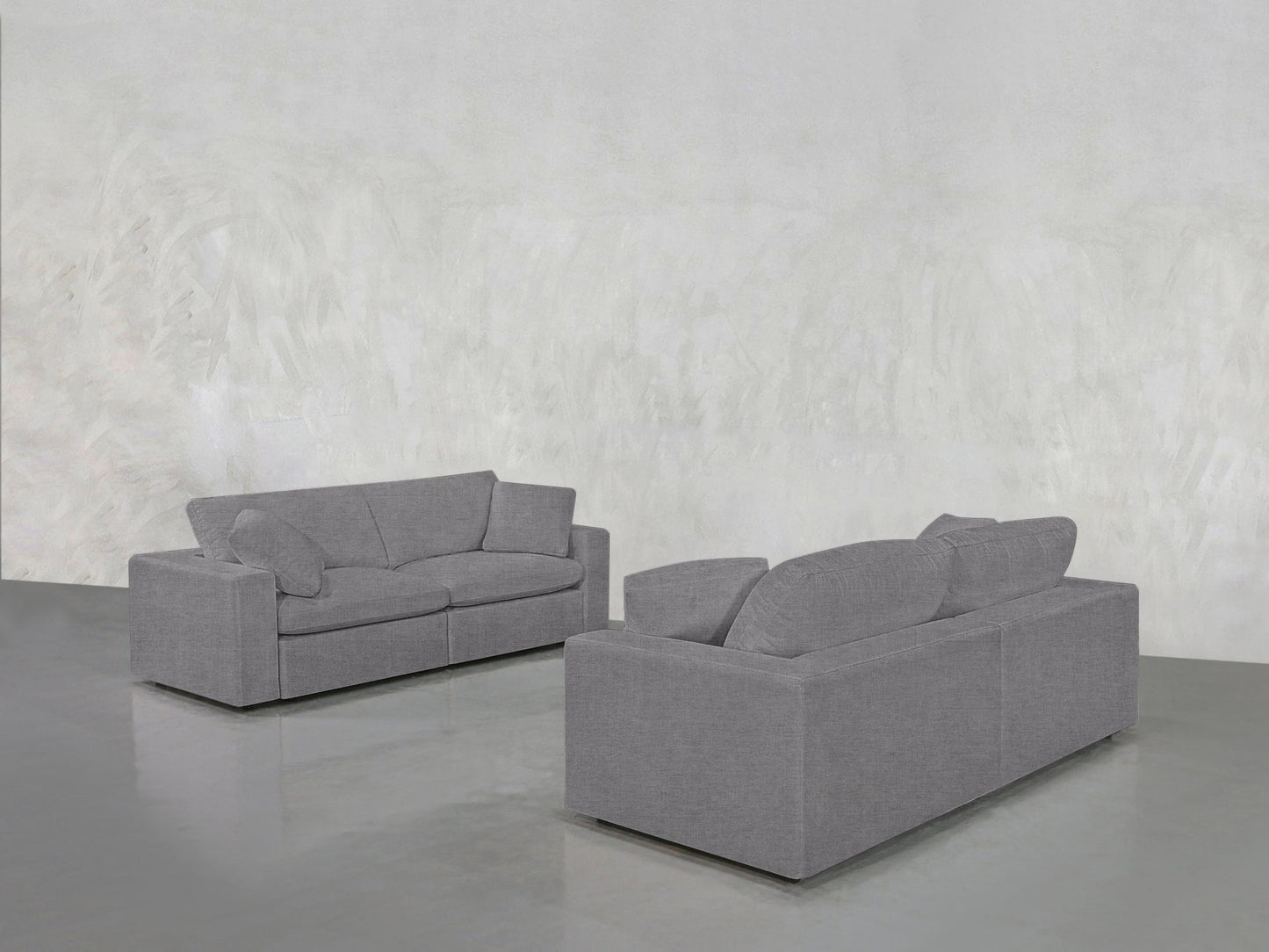 The 2-2 Sofa Set in modern gray is arranged facing each other in a minimalist room featuring light gray textured walls and a sleek, shiny gray floor.