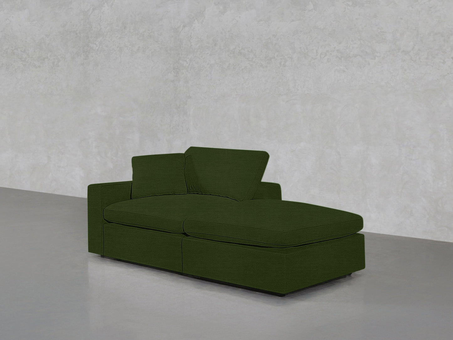 The 2-Seat Modular Lounger Loveseat in modern green stands against a light gray textured wall and polished gray floor, creating a minimalist vibe with its clean lines.