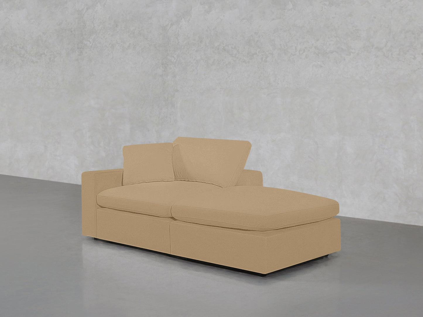 A 2-Seat Modular Lounger Loveseat in beige, featuring two matching cushions, is placed against a light gray textured wall and smooth gray floor in a minimalist room.