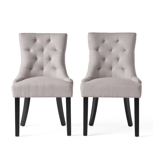 The Contemporary Cheney Dining Chair Set features two light gray, tufted upholstered chairs with black wooden legs, positioned side by side against a white background.