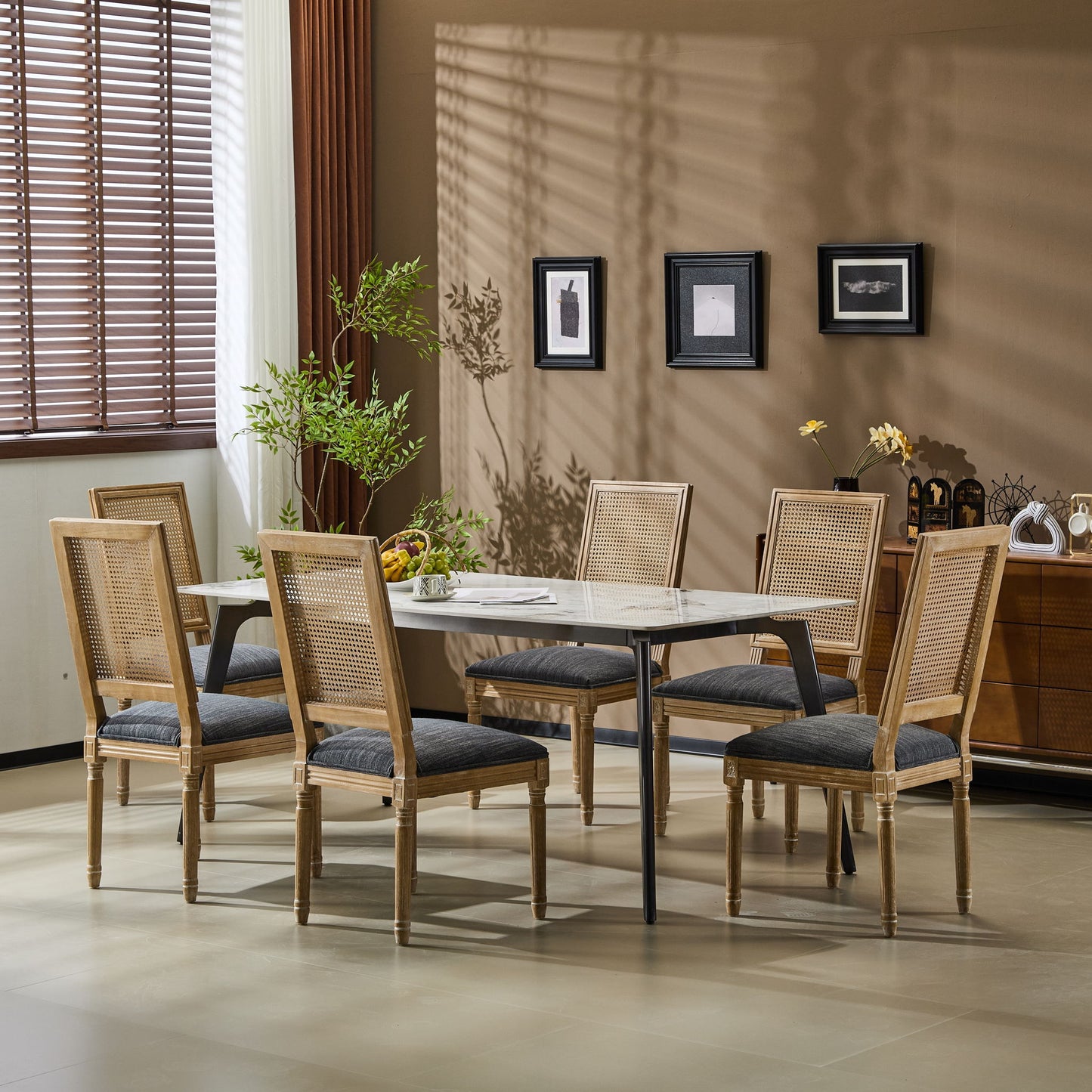 Six French Country Dining Chairs with rectangular cane backrests and smooth upholstered seats surround a marble dining table in a modern, sunlit room with beige walls, framed art, plants, and a window with blinds.