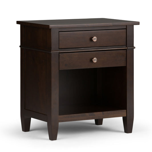 The Carlton - Bedside Table is a handcrafted dark wood nightstand with two drawers, an open middle shelf, sleek metal knobs, and tapered legs, shown on a white background.