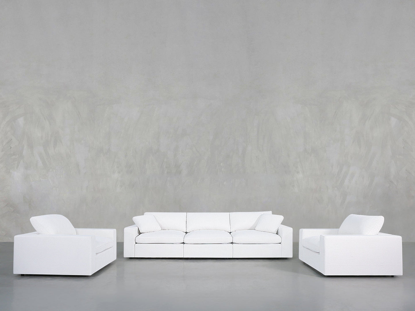 The 3-1-1 Sofa & Armchair Set is arranged in a U-shape in a minimalist room with a plain light gray wall and gray floor, creating a clean, uncluttered space that highlights simplicity and spaciousness.