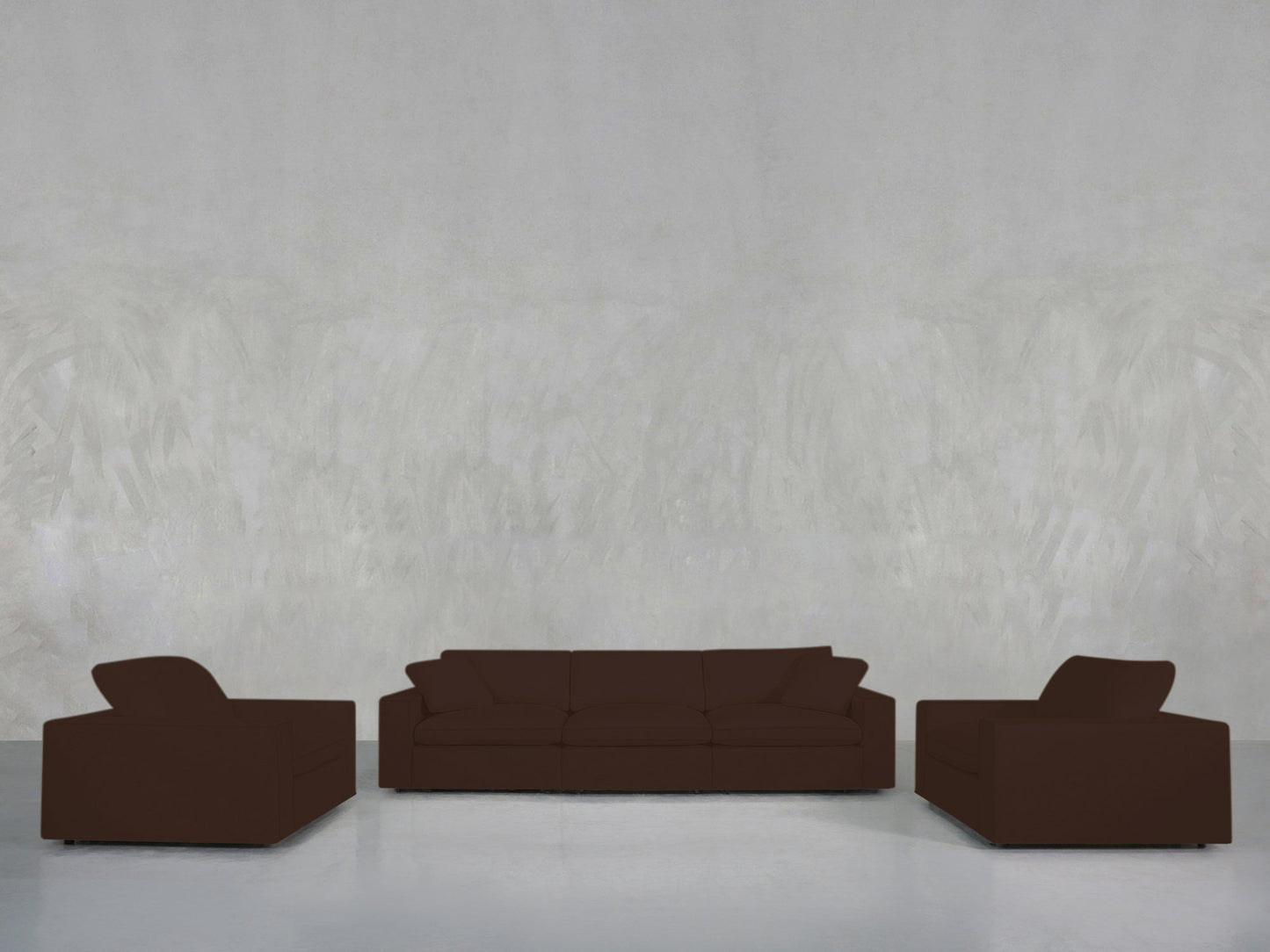 A minimalist room with a concrete-style gray wall, featuring the 3-1-1 Sofa & Armchair Set in dark brown—a central three-seater sofa and two matching armchairs—arranged on a smooth, light-colored floor.