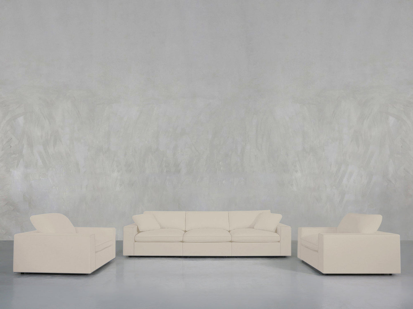 A minimalist living room features the 3-1-1 Sofa & Armchair Set, with a cream three-seater sofa and matching armchairs arranged on a smooth light floor against a textured light gray wall.