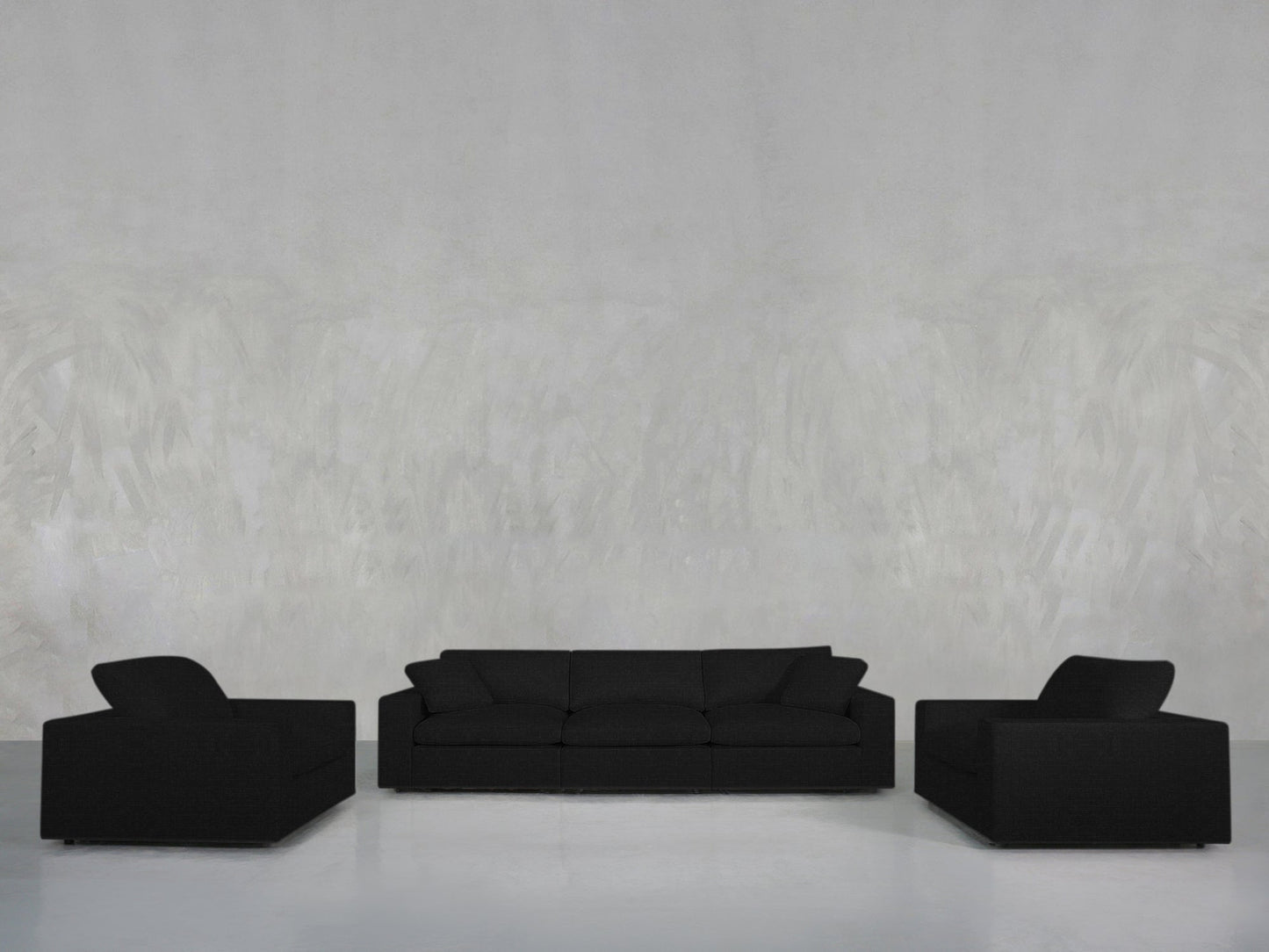 The 3-1-1 Sofa & Armchair Set—one three-seater flanked by two single armchairs in black upholstery—is arranged against a light gray textured wall on a glossy white floor.