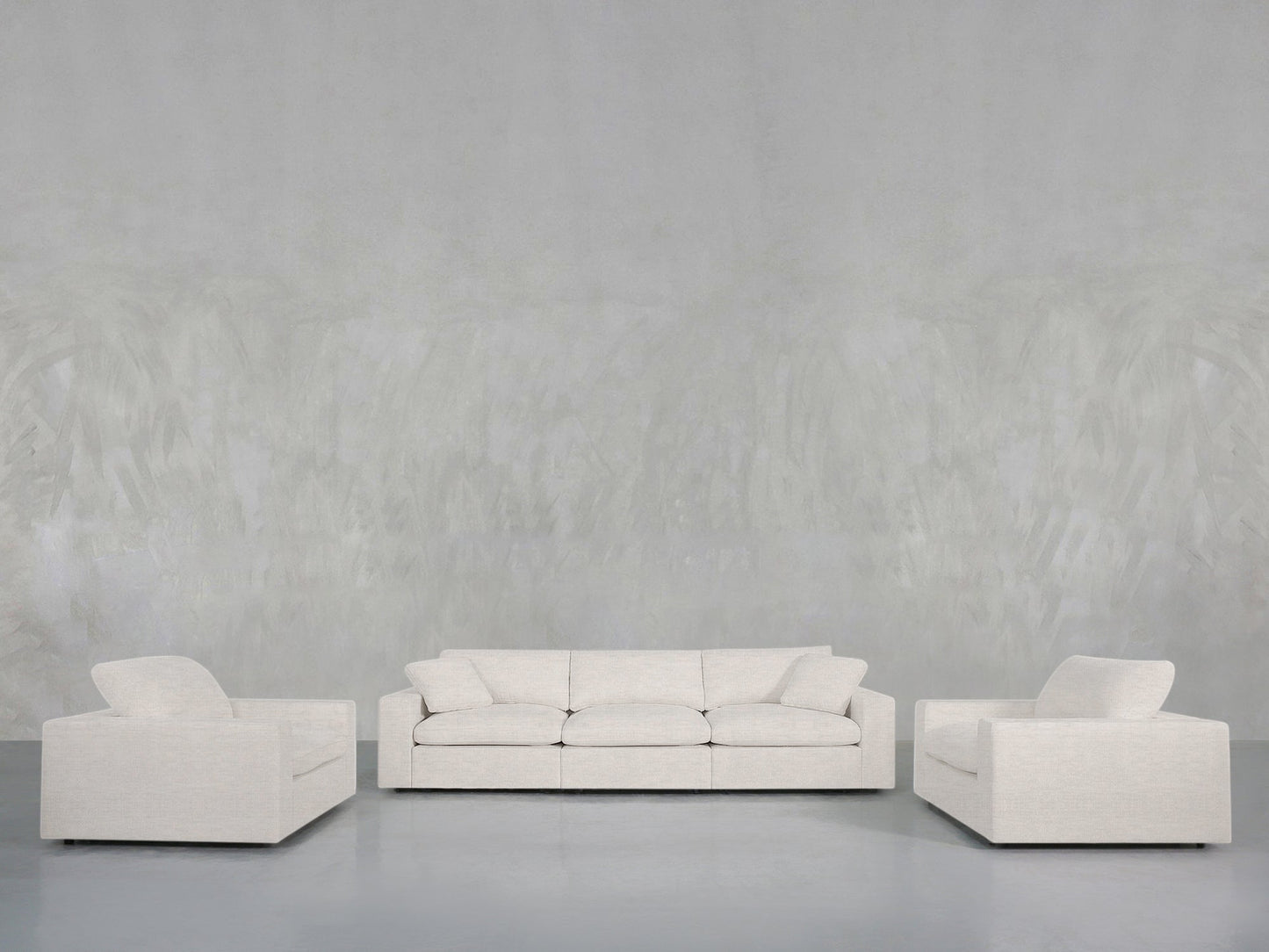 The 3-1-1 Sofa & Armchair Set, featuring a light gray sofa and two matching armchairs with clean lines and modern design, is arranged in a minimalist living room against a textured gray wall and floor.