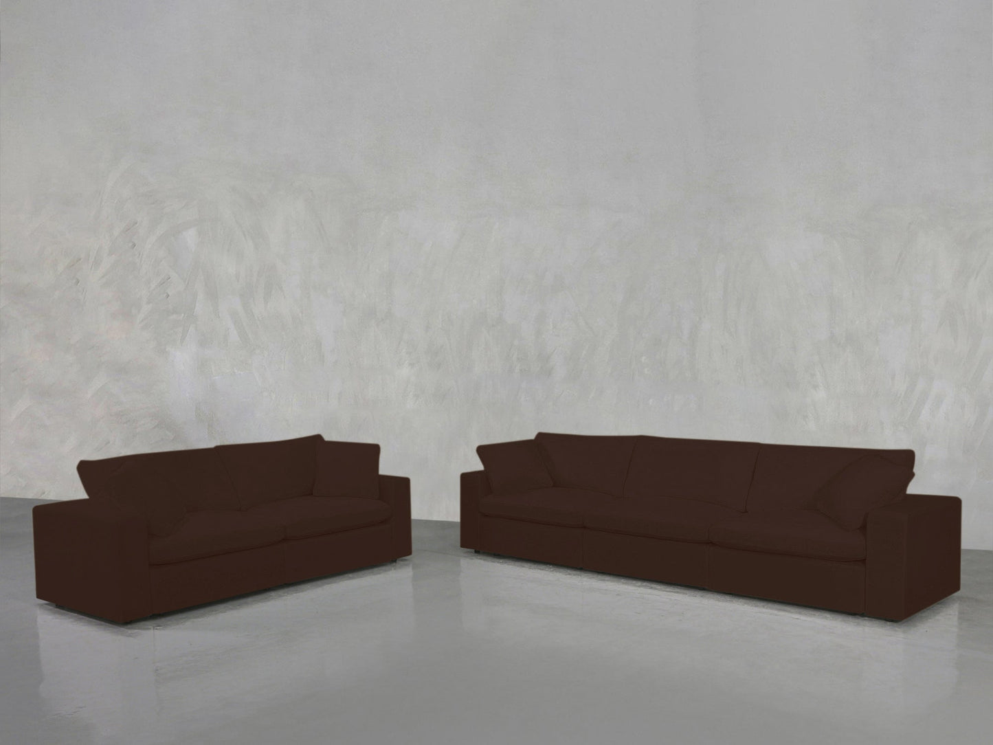 The 3-2 Sofa Set, featuring a dark brown two-seater and three-seater, is placed apart on a shiny light gray floor against a textured light gray wall.
