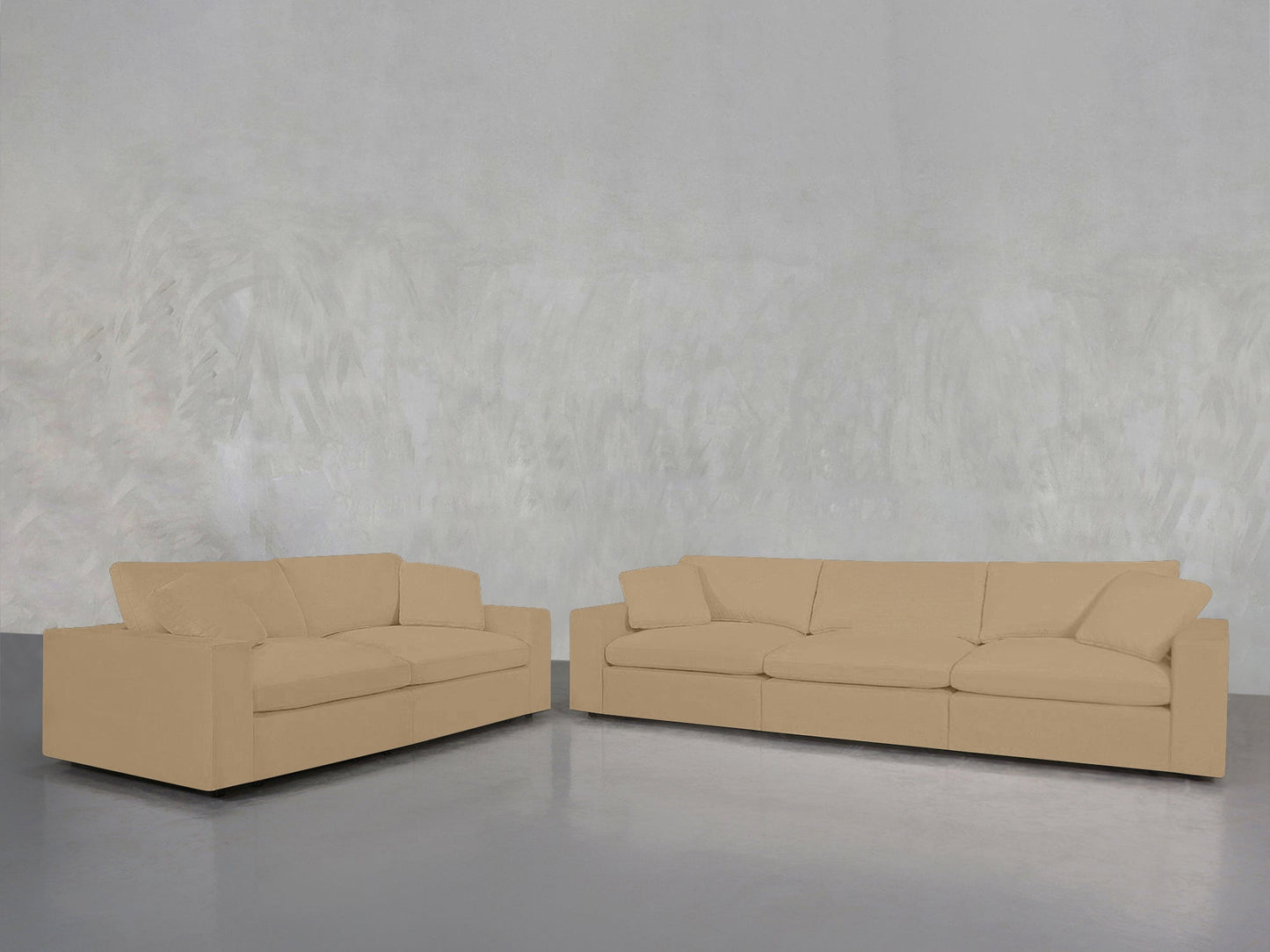 The 3-2 Sofa Set, featuring one larger and one smaller beige sofa, is arranged at an angle in a minimalist room with a light gray textured wall and shiny gray floor.