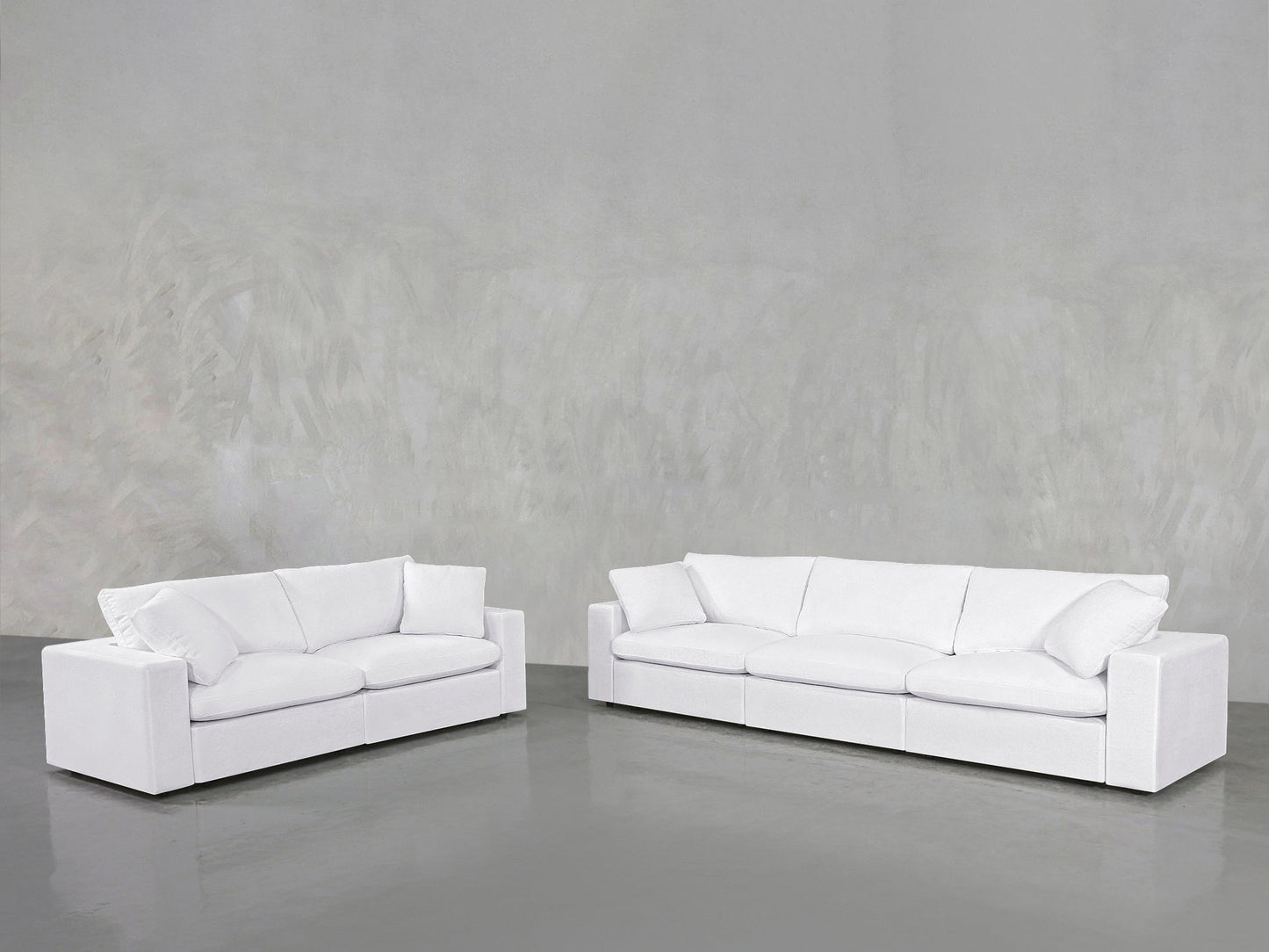 A 3-2 Sofa Set with plush white cushions is placed against a plain, light gray textured wall on a shiny gray floor in a minimalist room.