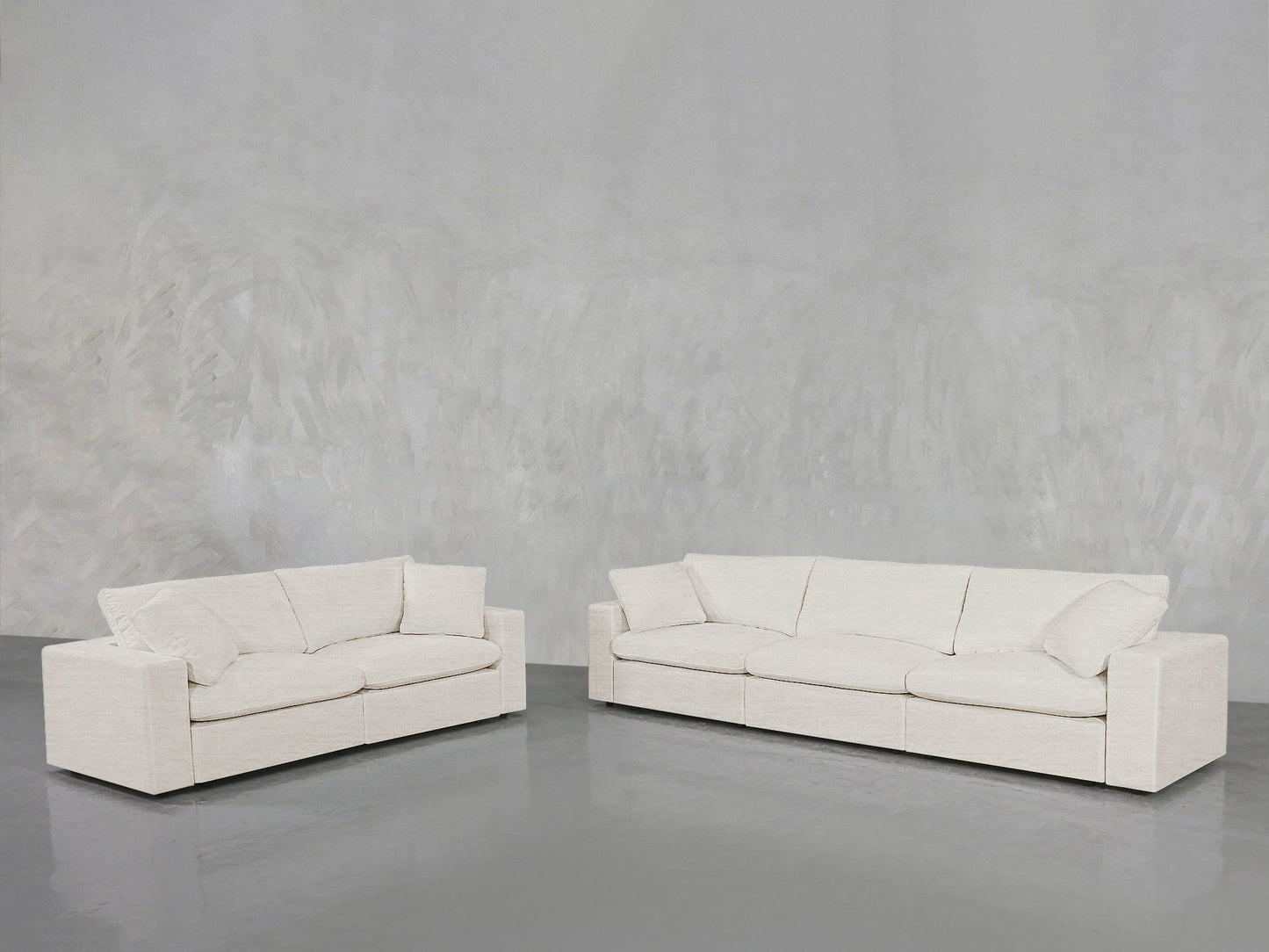 The 3-2 Sofa Set, featuring modern light beige upholstery with clean lines and plush cushions, is arranged on a polished gray floor against a textured light gray wall in a minimalist space.