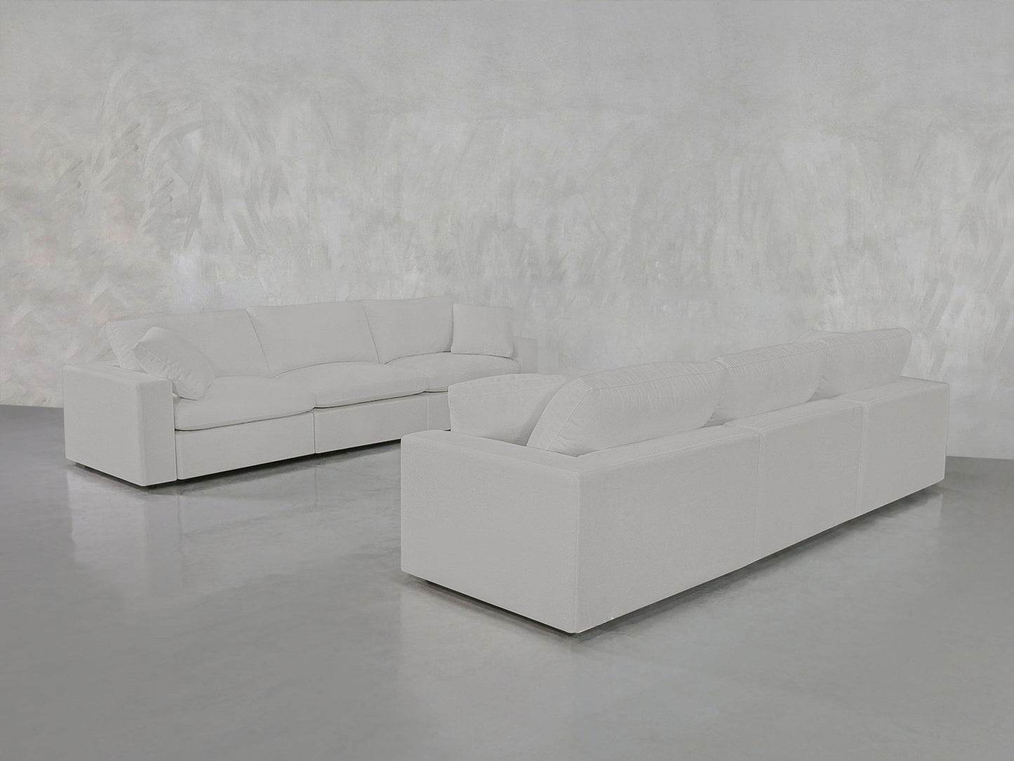 Two 3-3 Sofa Sets with clean lines are arranged in an L-shape in a minimalist room featuring a textured white wall and a shiny gray floor.