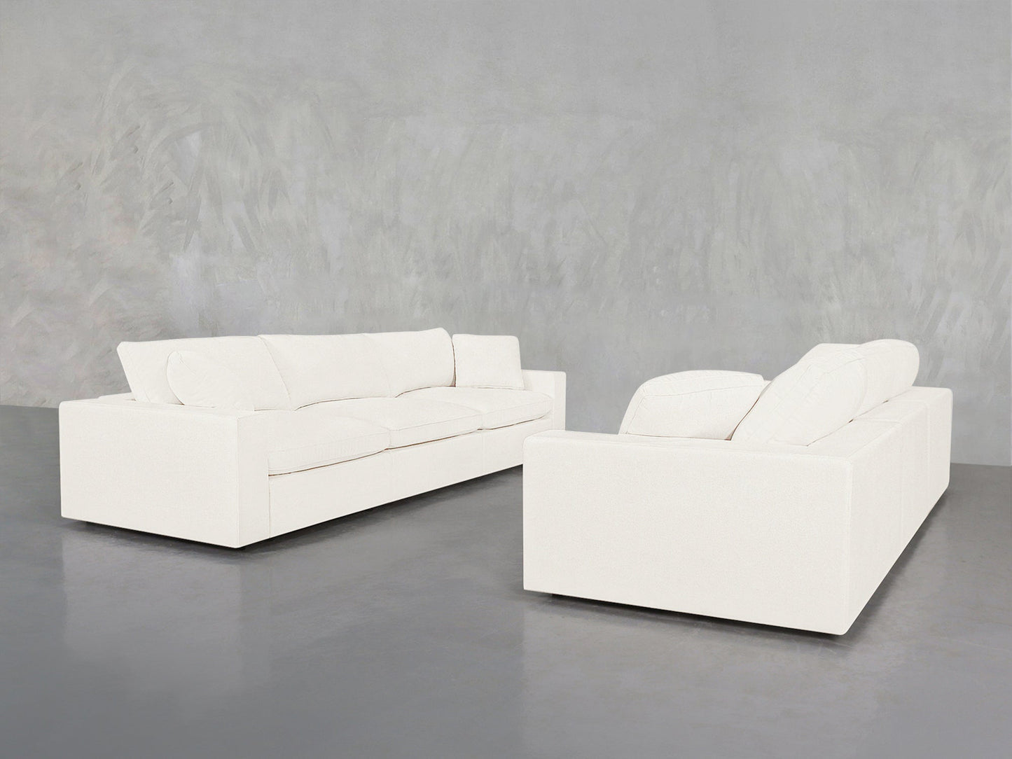 Two 3-3 Sofa Sets with clean, modern lines face each other in a minimalist room featuring a gray textured wall and polished concrete floor.