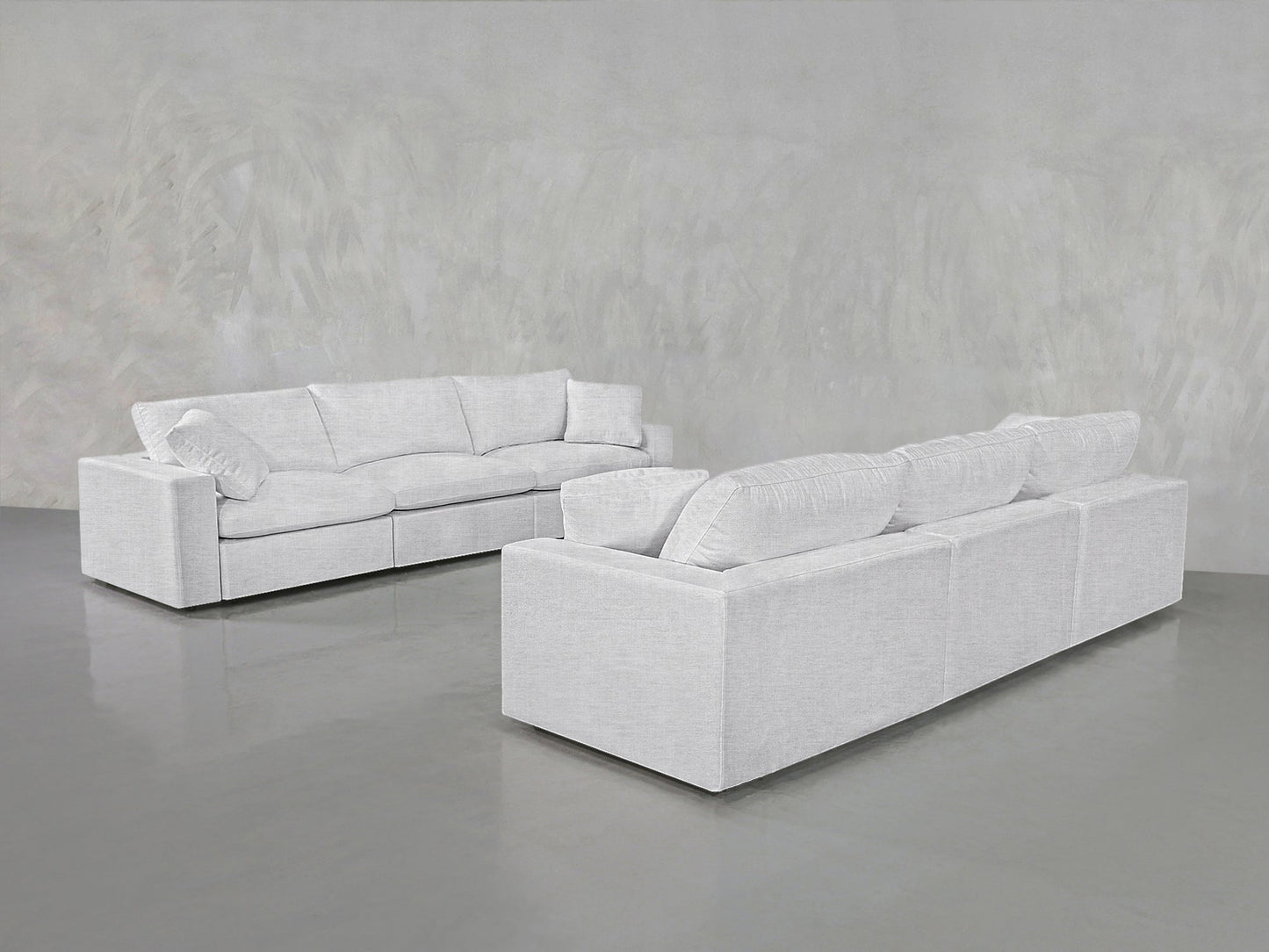 Two 3-3 Sofa Sets with plush cushions are arranged facing each other in a minimalist room featuring light gray walls and a glossy gray floor.