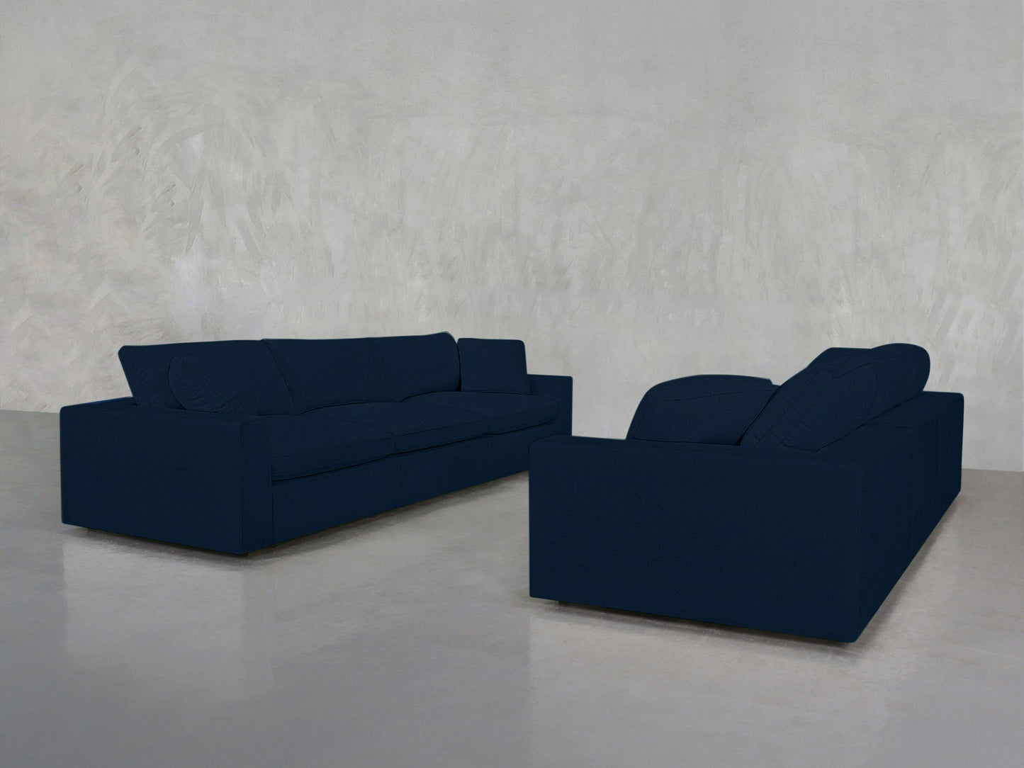 Two 3-3 Sofa Sets in dark blue are placed on a polished concrete floor against a light gray textured wall in a minimalistic, empty room.