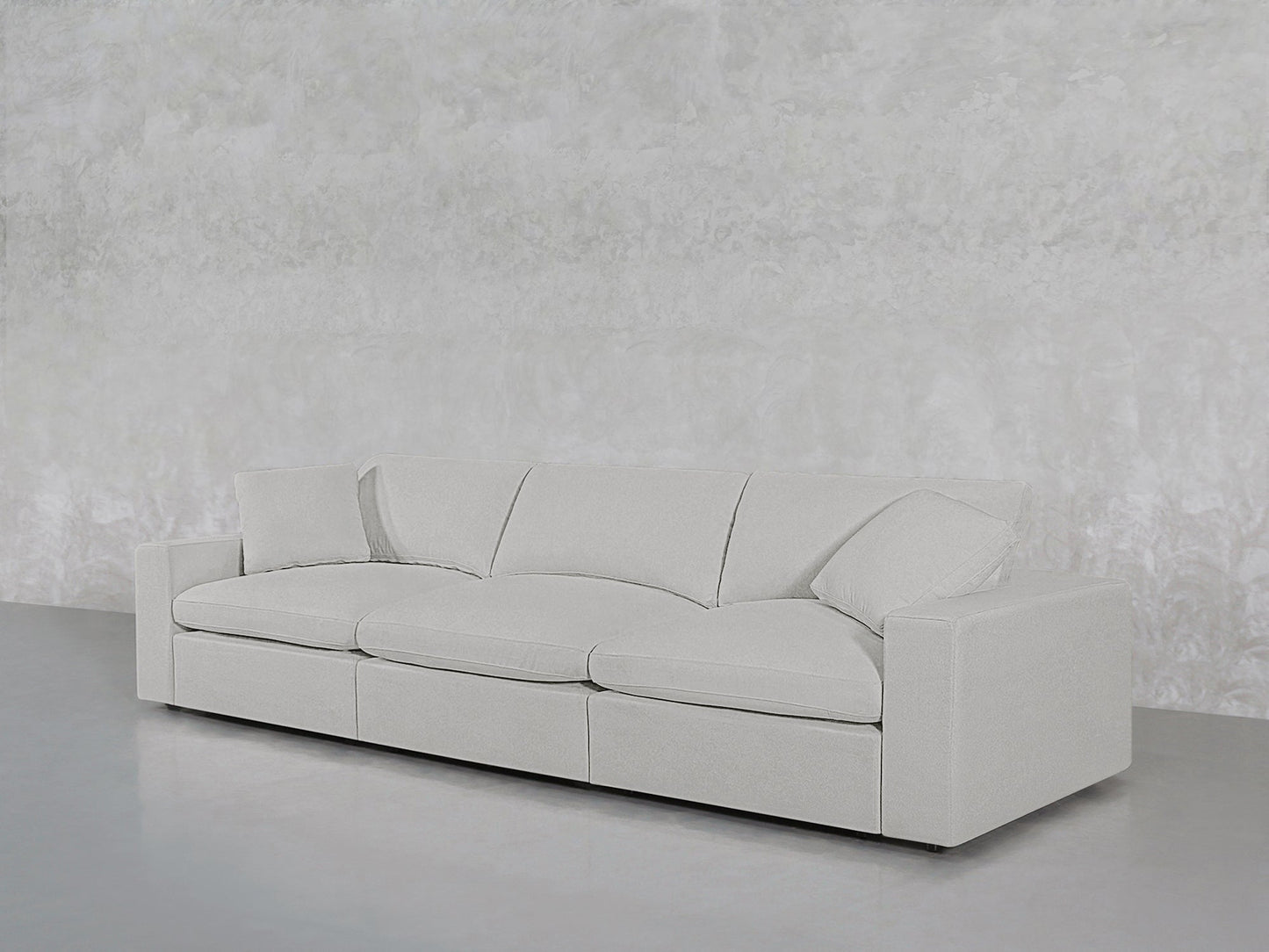 The 3-Seat Modular Sofa in modern light gray, featuring clean lines and plush cushions, sits against a textured light gray wall on a polished gray floor.