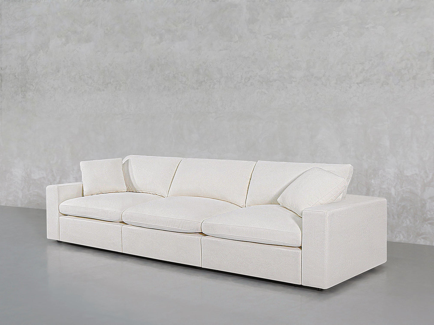 A 3-Seat Modular Sofa in modern white with clean lines and plush cushions sits against a light grey textured wall on a smooth grey floor.