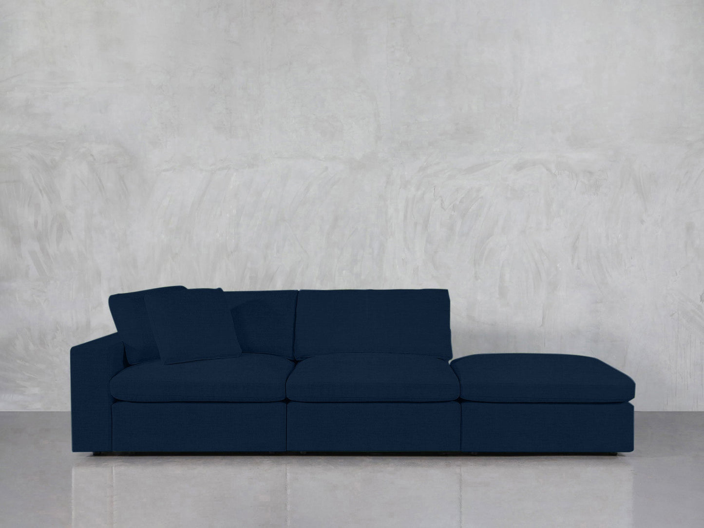 A 3-Seat Modular Lounger Sofa in dark blue, featuring three seat cushions and two back cushions, is set against a light gray textured wall on a light-colored tiled floor.