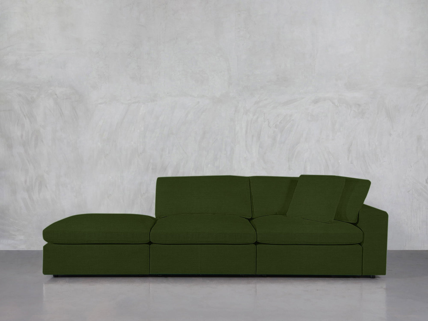A 3-Seat Modular Lounger Sofa in green with a left-side chaise sits against a plain light gray textured wall on a smooth, polished floor.