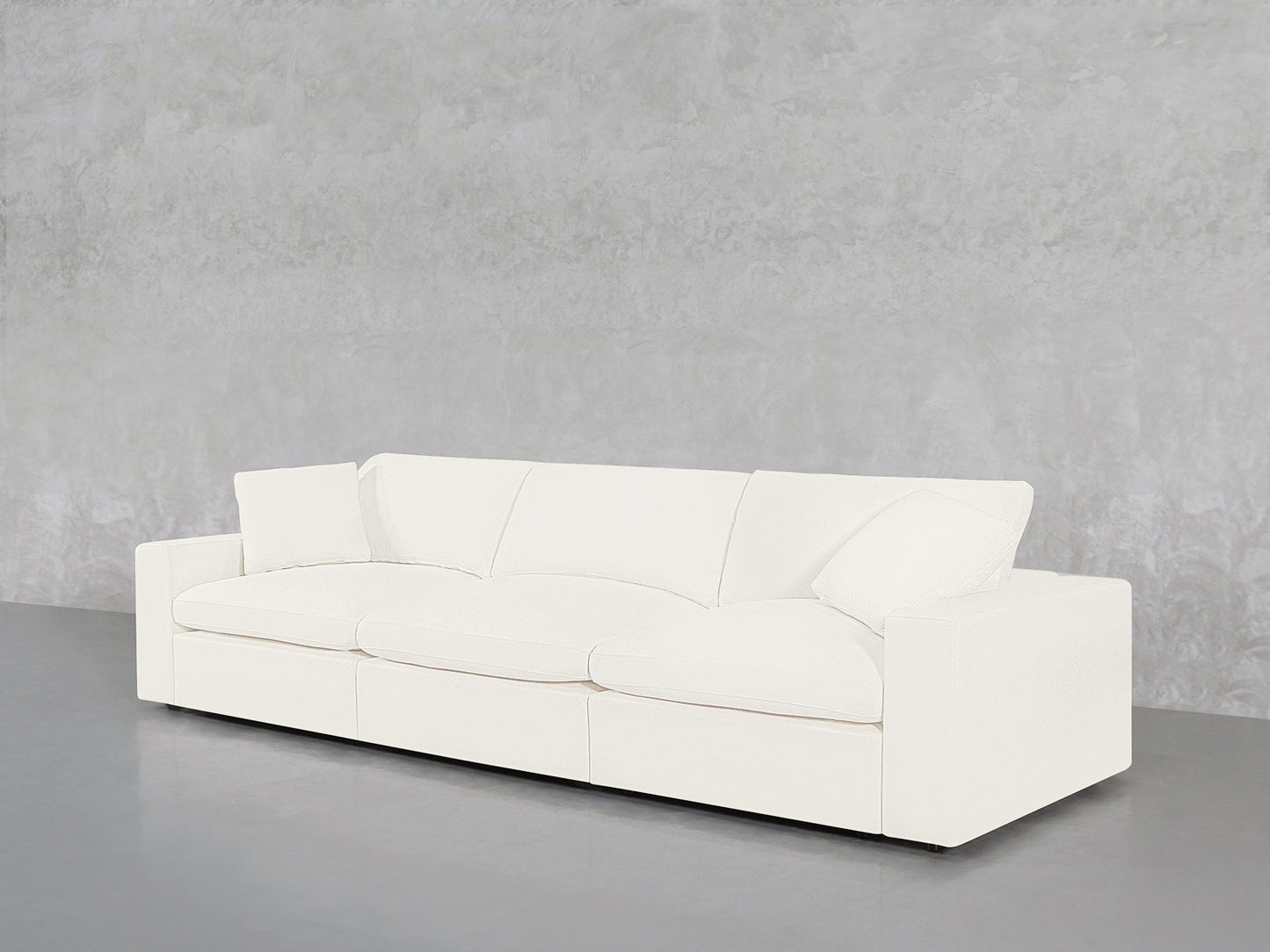 The 3-Seat Modular Sofa with clean lines and plush cushions is placed against a light gray textured wall and set on a smooth, gray floor.