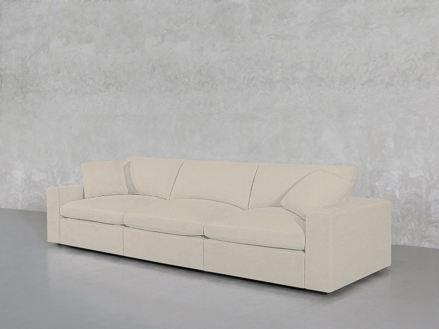 The 3-Seat Modular Sofa in light beige with clean lines and rectangular cushions is placed against a textured light gray wall on a smooth gray floor.