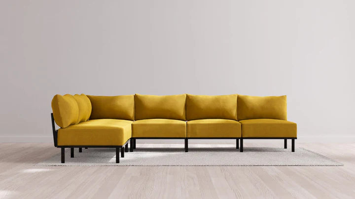 An Indoor Jack 6-Seater Open-Ends Corner Sectional in Balsa is placed on a light gray rug, set against a plain light gray wall. The sectional sofa features a left-facing chaise, black metal legs, and a minimalist design.