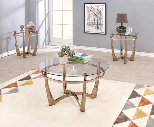 A modern living room with light wood floors, featuring three Orlando - Clear Glass Coffee Tables in champagne, a white geometric rug, and artwork on the gray wall.