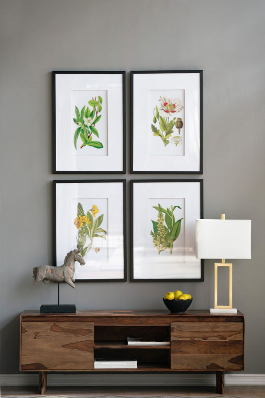 A wooden console table with a horse statue, lemons, and a modern lamp sits against a gray wall, above which the Botanical Flower Wall Art (Set of 4, White/Blue) is neatly arranged in black frames.
