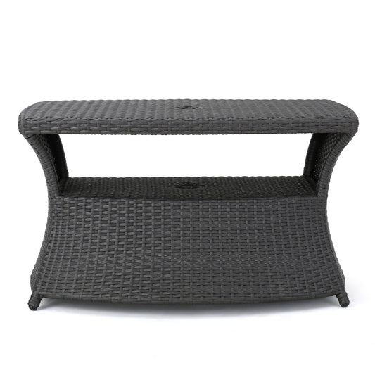 The Berkeley - Chaise Lounge Side Table features a rectangular, dark brown woven wicker design with curved sides, an open shelf under the tabletop, and stands on four legs.