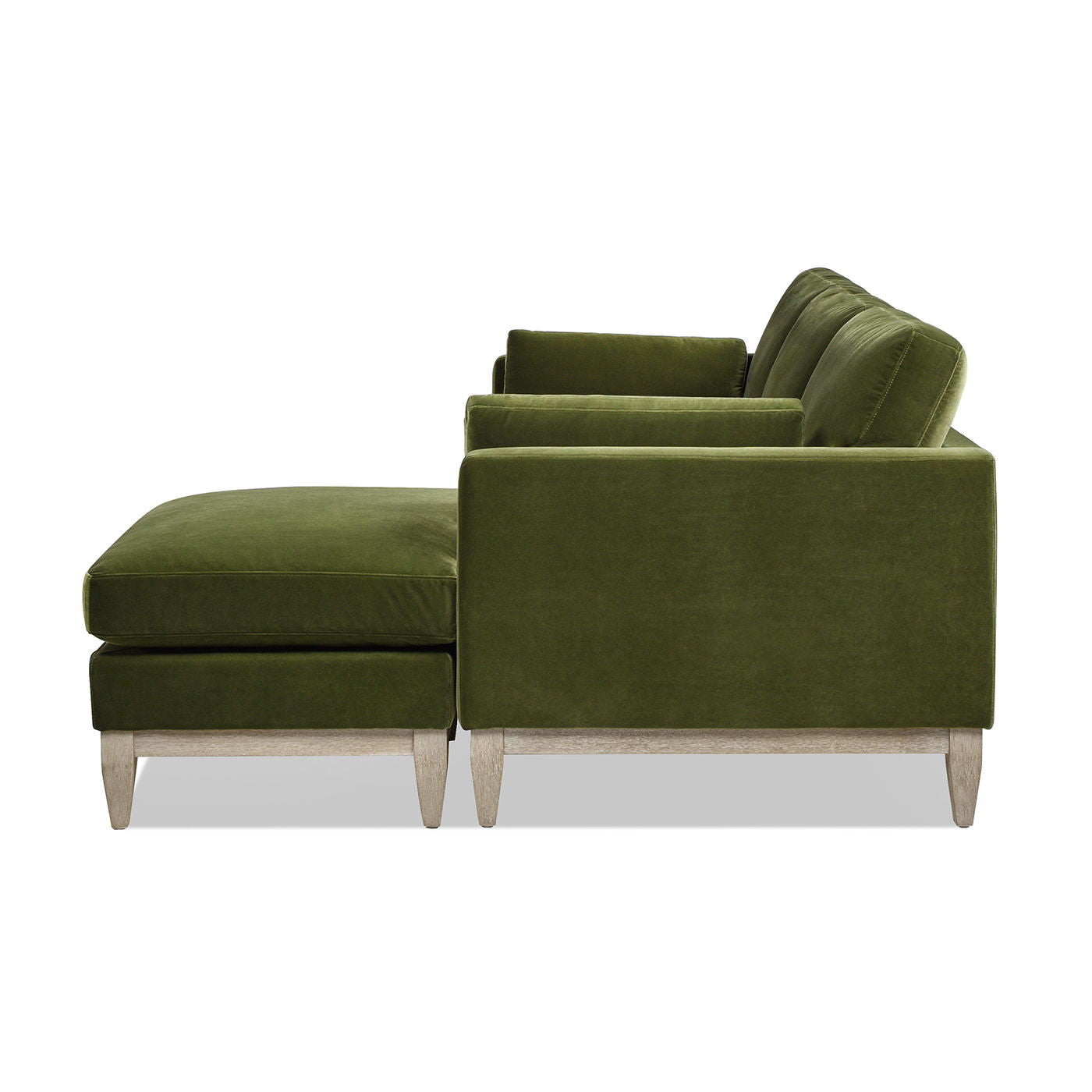 Side view of the Knox - Modern Farmhouse Reversible Chaise Sectional Sofa in green velvet, shown with matching ottoman, clean lines, plush cushions, and light wooden legs.