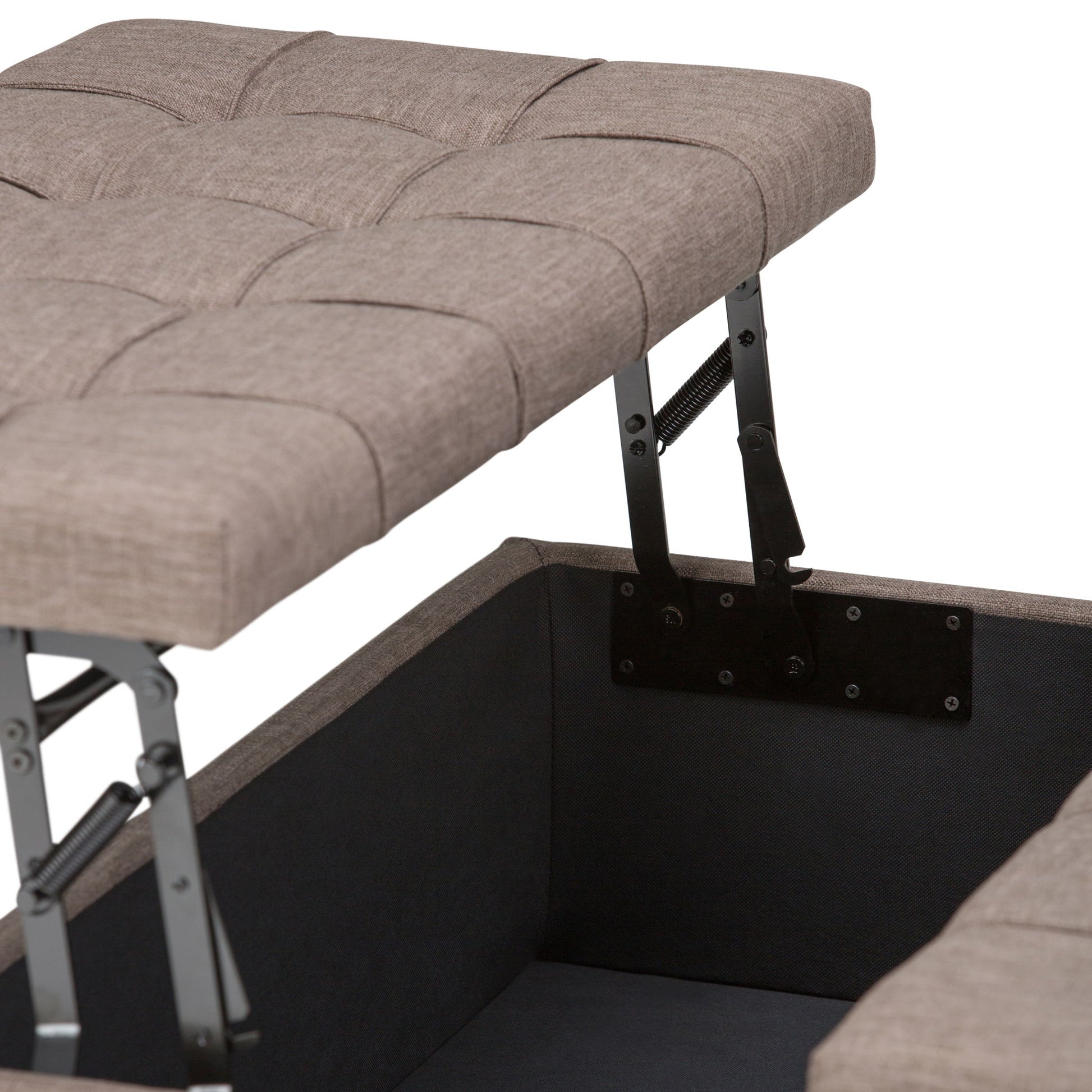 Close-up of the Harrison Upholstered Coffee Table Storage Ottoman with a tufted, cushioned lid propped open on metal hinges, showing its inner storage compartment. The exterior features light brown fabric upholstery.