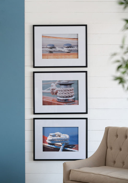The Boater Knots Wall Art With Frame (Set of 3) - Multicolor is displayed vertically on a white shiplap wall beside a light brown chair, with a blue accent wall and green plant partially visible in the living room.