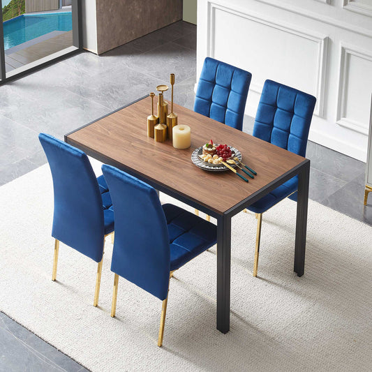 The 5 Pieces Dining Set includes a creative rectangular table and four velvet high-back chairs with gold legs, arranged on a light rug in a modern room and adorned with candles, gold decor, and fruit.