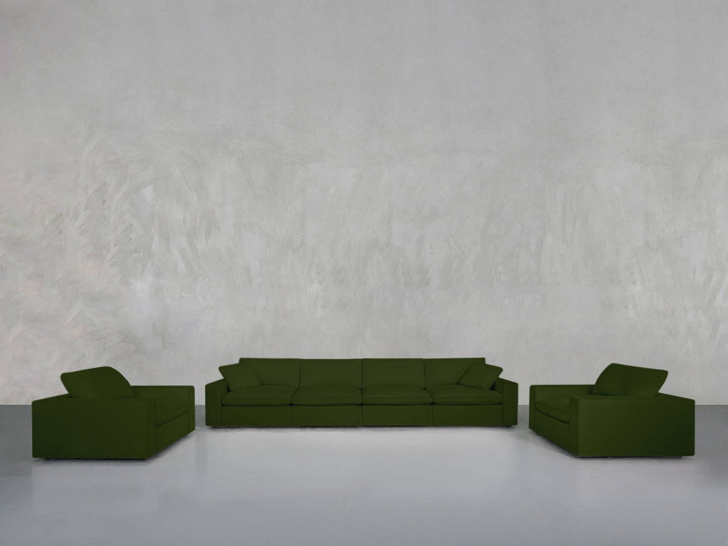 A minimalist room with a light gray textured wall showcases the 4-1-1 Sofa & Armchair Set in dark green at its center, framed by matching armchairs on a smooth light gray floor.