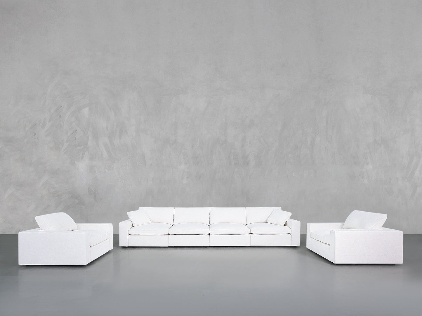 A minimalist living room showcases the 4-1-1 Sofa & Armchair Set, featuring a modern white sofa and two matching armchairs with clean lines, set against a smooth grey wall and floor.
