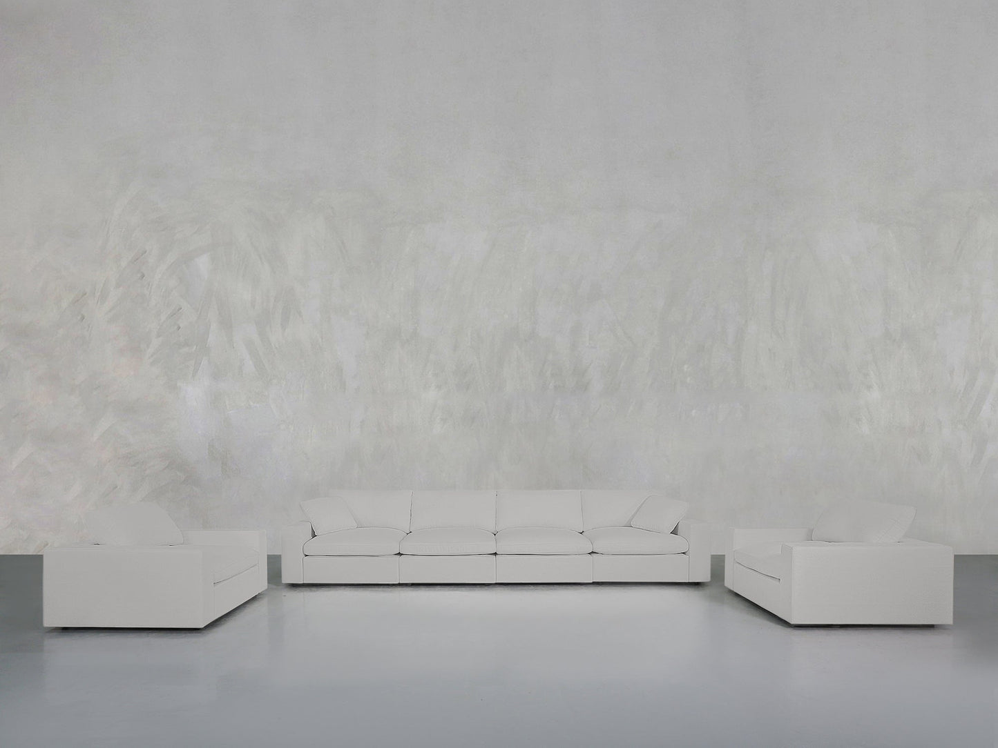 A minimalist living room with a light gray textured wall features the 4-1-1 Sofa & Armchair Set: a white three-seater sofa in the center and two matching white armchairs on either side, all placed on a smooth gray floor.