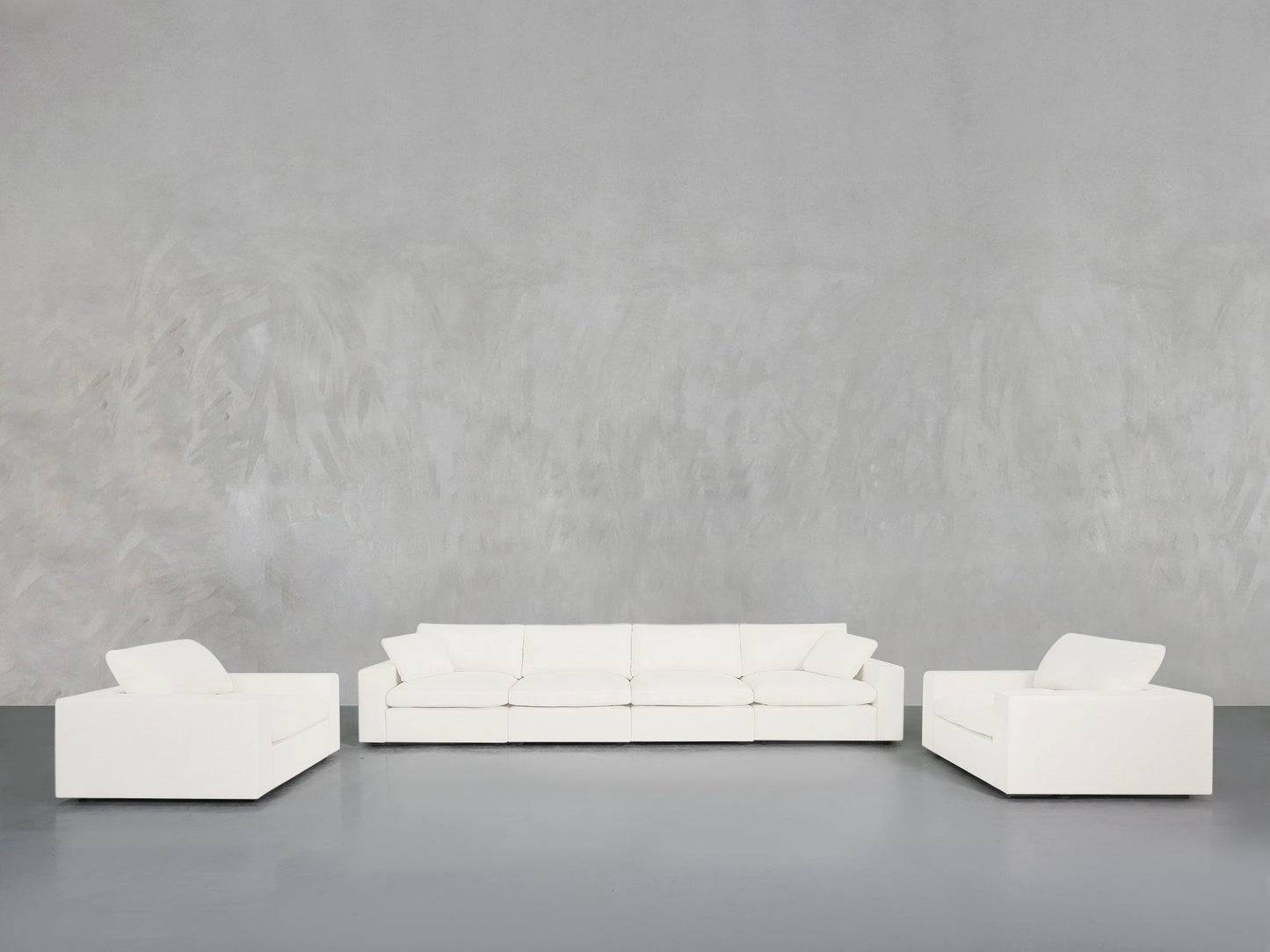 The 4-1-1 Sofa & Armchair Set is showcased in a minimalist space with a light gray textured wall and smooth gray floor, creating a clean and spacious atmosphere.