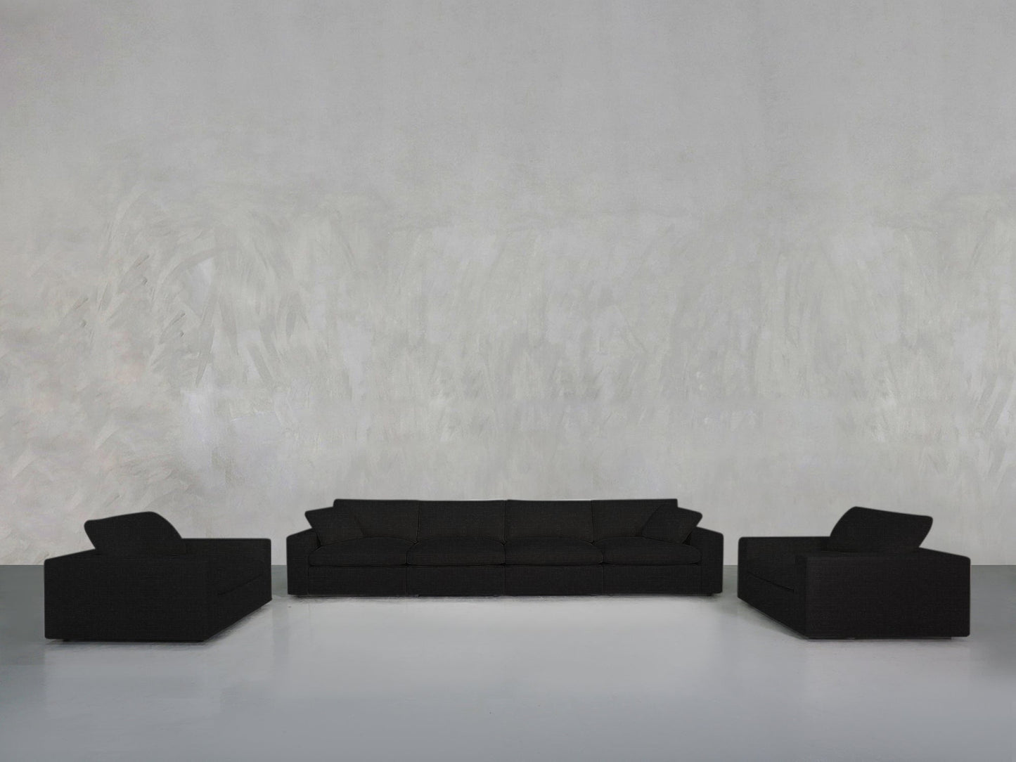 A minimalist room with a light gray textured wall showcases the 4-1-1 Sofa & Armchair Set: a black three-seat sofa centered between two matching black armchairs on a glossy light floor.
